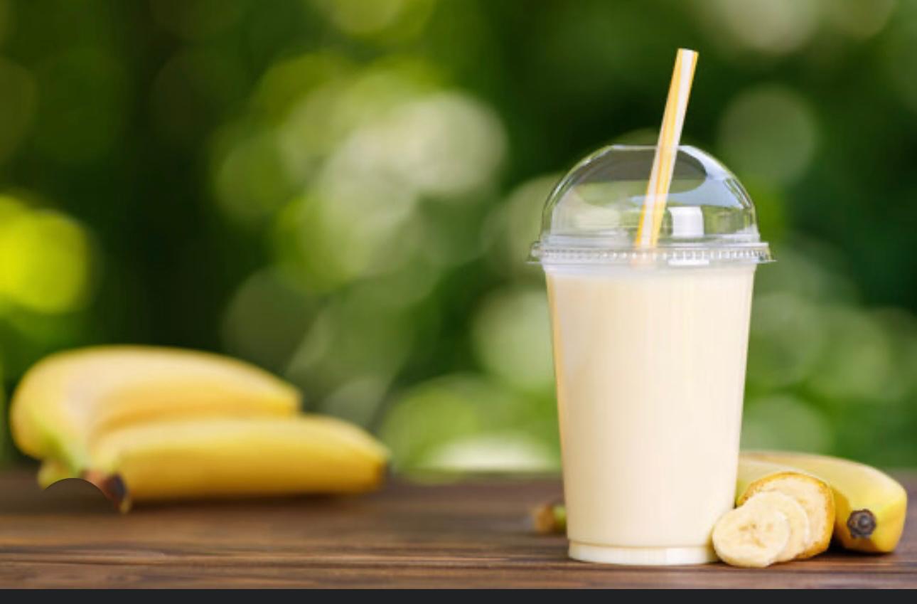 Banana milkshake on a nice background, with a few bananas decorating it 
