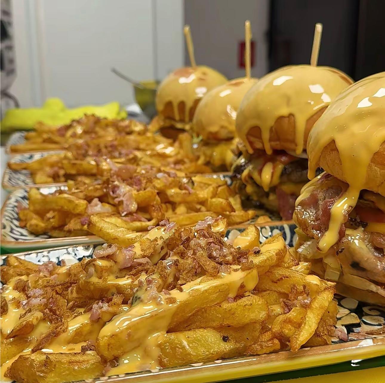 several trays with gorgeous burgers, dripping melted cheese, and bacon topped fries