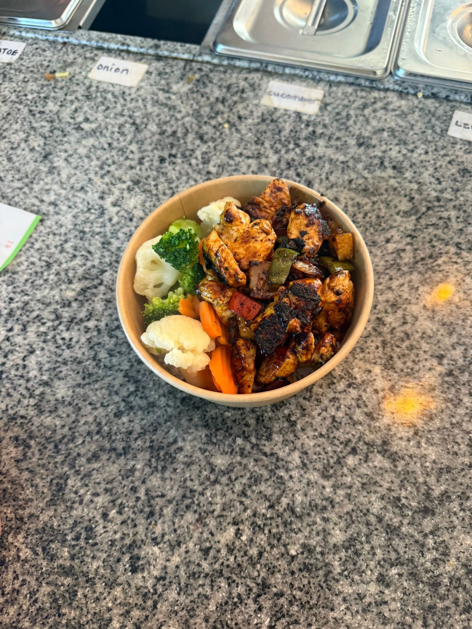 A pair of meal prep bowls on a rustic wooden table. One bowl contains pasta topped with rich tomato sauce and meatballs. The second bowl features a slice of lasagna served with peas and sweetcorn.