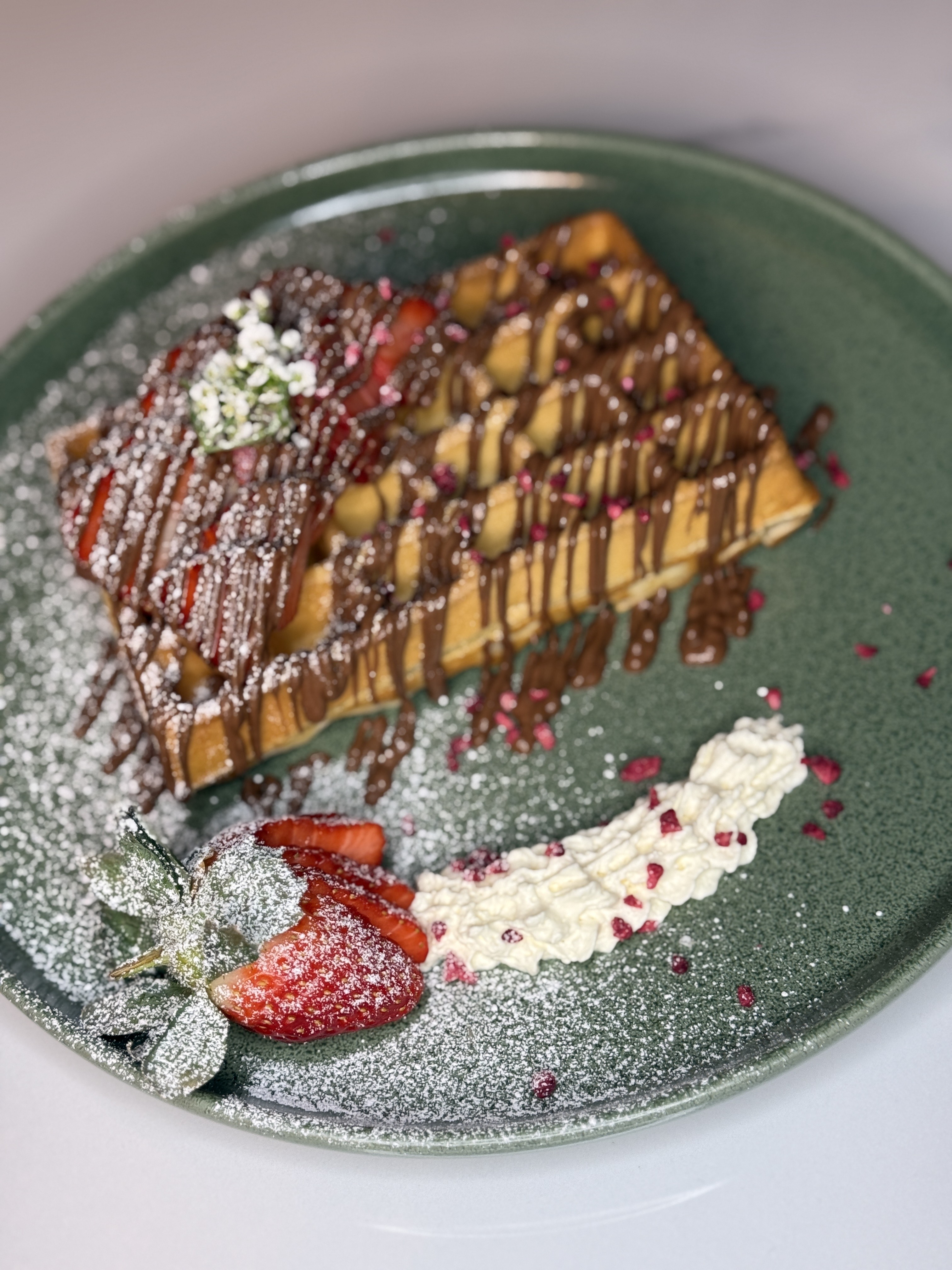 Strawberry waffle topped with nutella and milk chocolate sauce