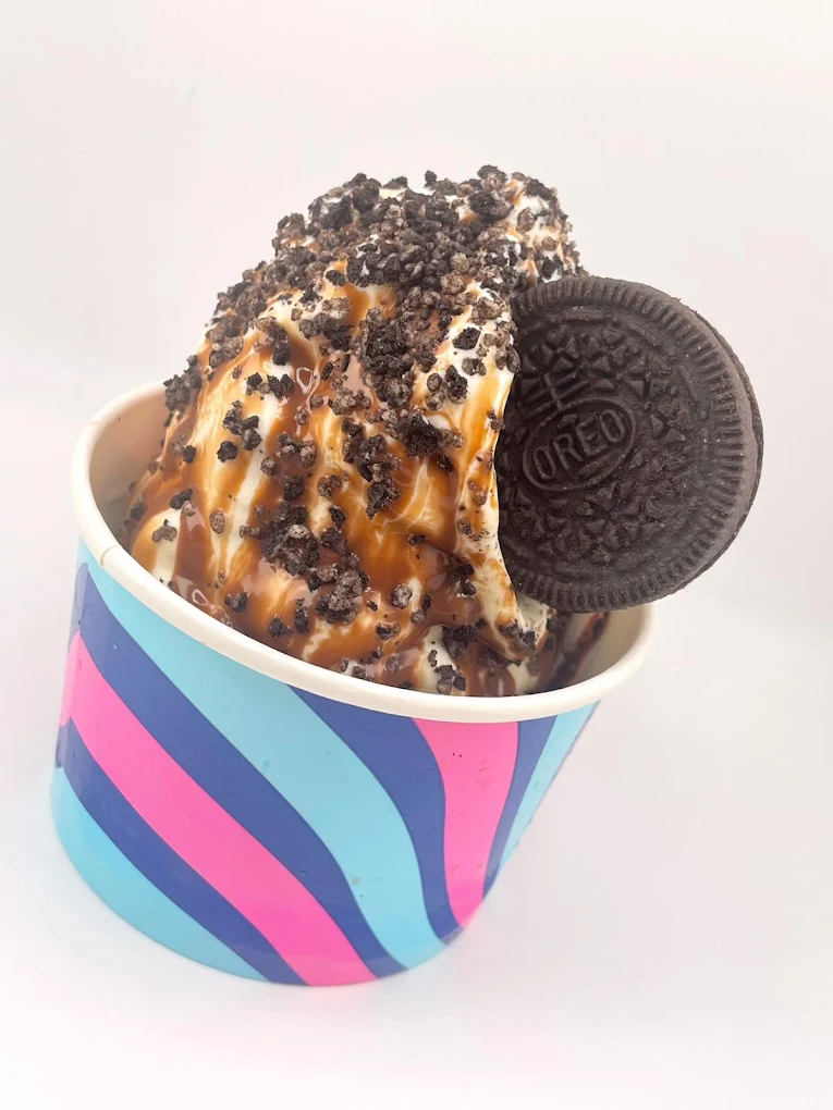 Creamy Oreo ice cream sundae topped with crushed Oreo cookies and caramel drizzle, served in a colourful takeaway cup.