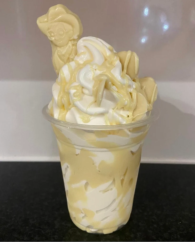 Vanilla ice cream sundae generously drizzled with white chocolate sauce and topped with white chocolate pieces.