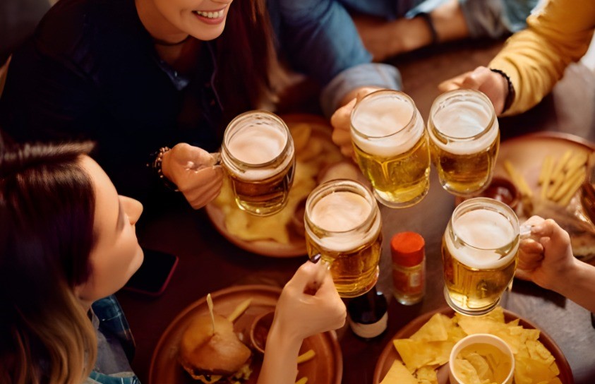 Un groupe d'amis qui entrechoquent des bières commandées chez Apéro Minute.