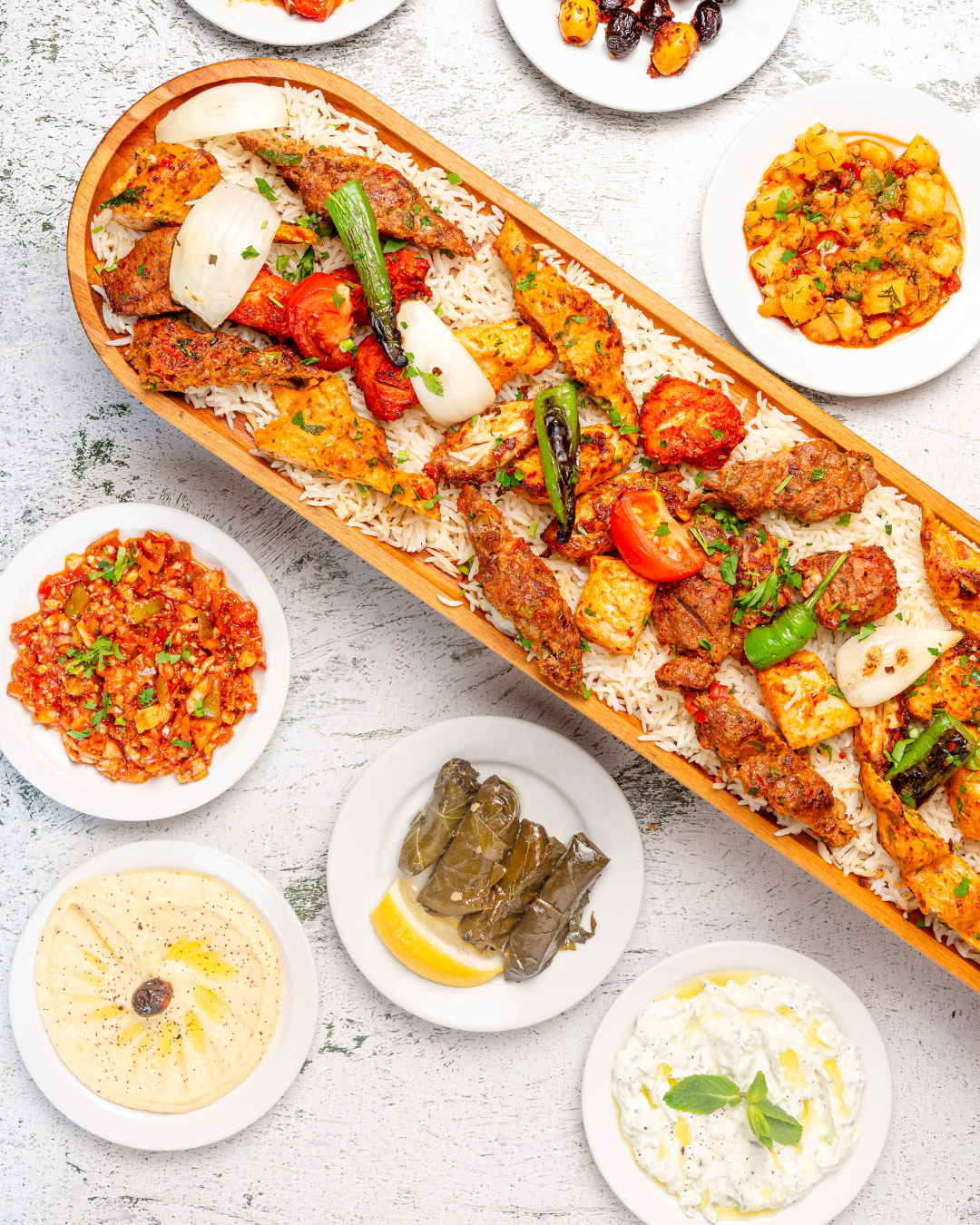 Turkish charcoal grill platter with juicy kebabs, rice and fresh Mediterranean side dishes.