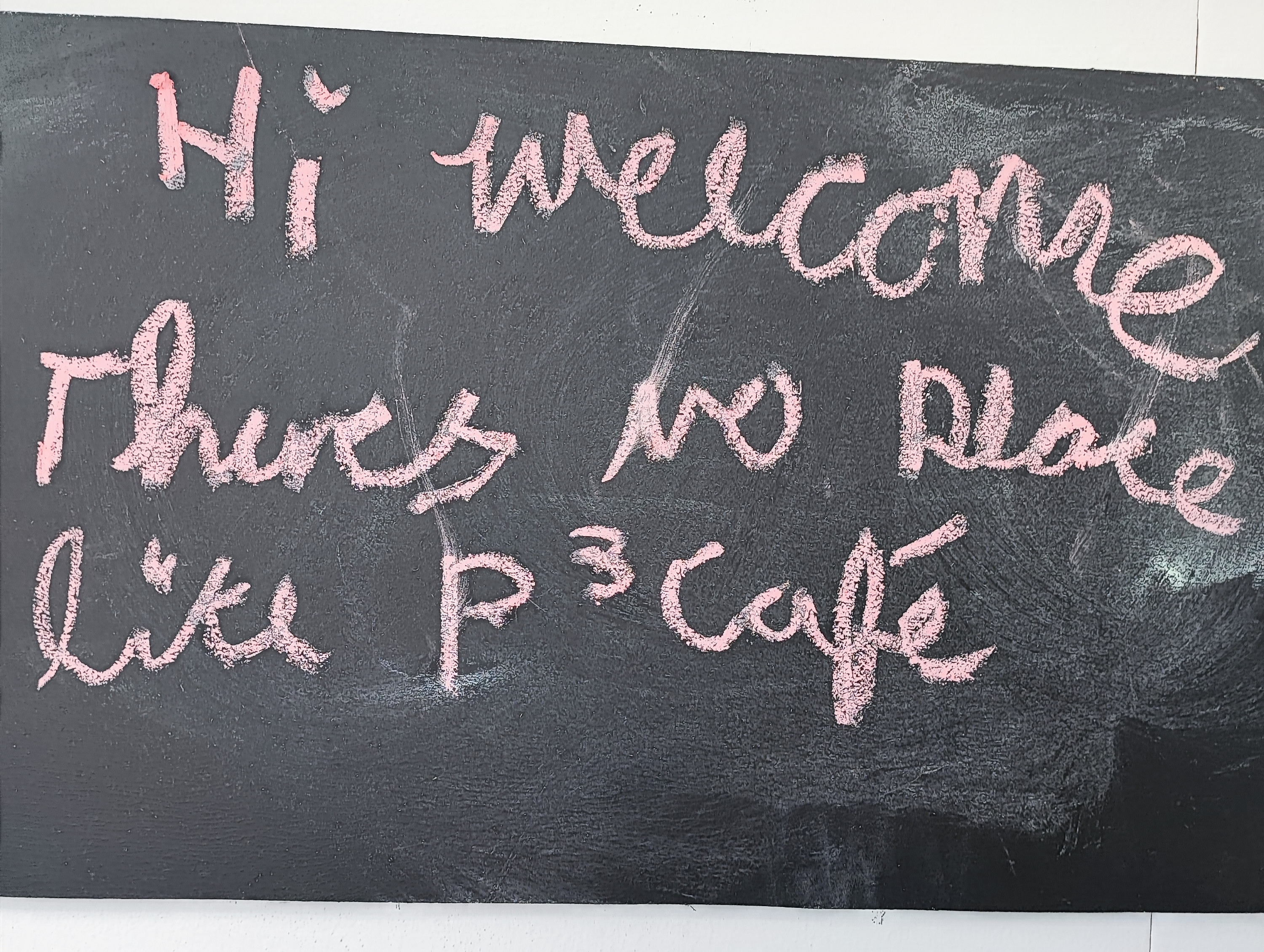 Blackboard with pink writing. "Hi welcome there's no place like P³ Café" as reviewed by Lauren 