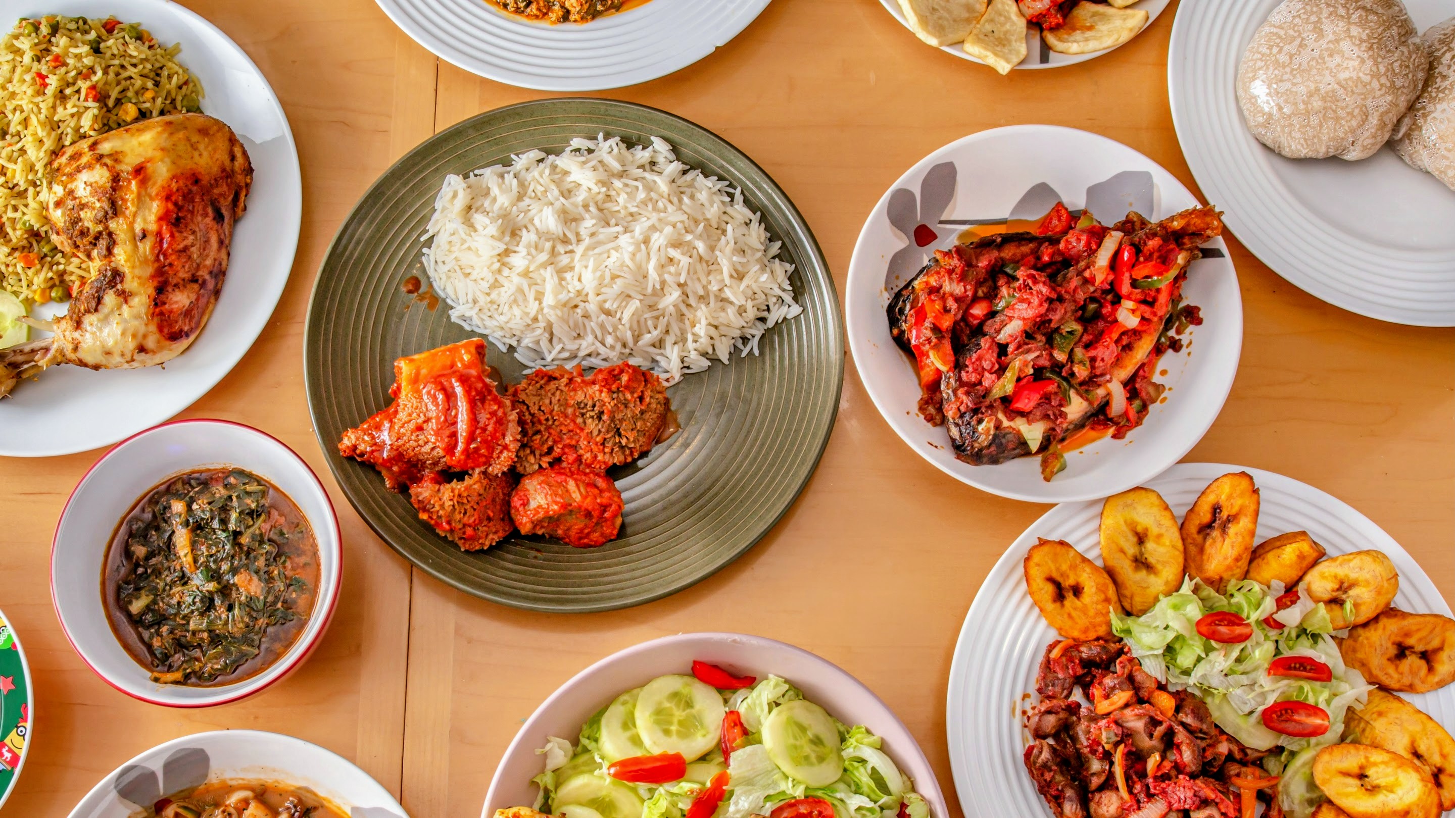 Assortment of African dishes to quench your hunger, fried rice, cooked white rice with stew and beef, garnished tilapia fish, fried plantain and more.